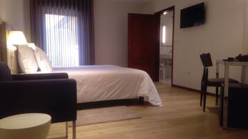 Een hotelkamer met een bed, een bureau, een stoel, een televisie en een lamp.