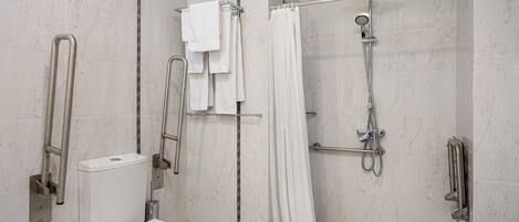 A modern bathroom with a toilet, a shower with a handheld showerhead, and a bathtub.
