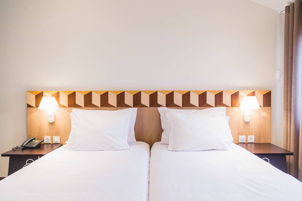 Ein Doppelbett mit Holz Kopfteil, zwei Nachttischlampen, ein Telefon und ein Nachttisch.