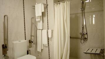 Un baño con inodoro, ducha con puerta de cristal y barra para toallas.