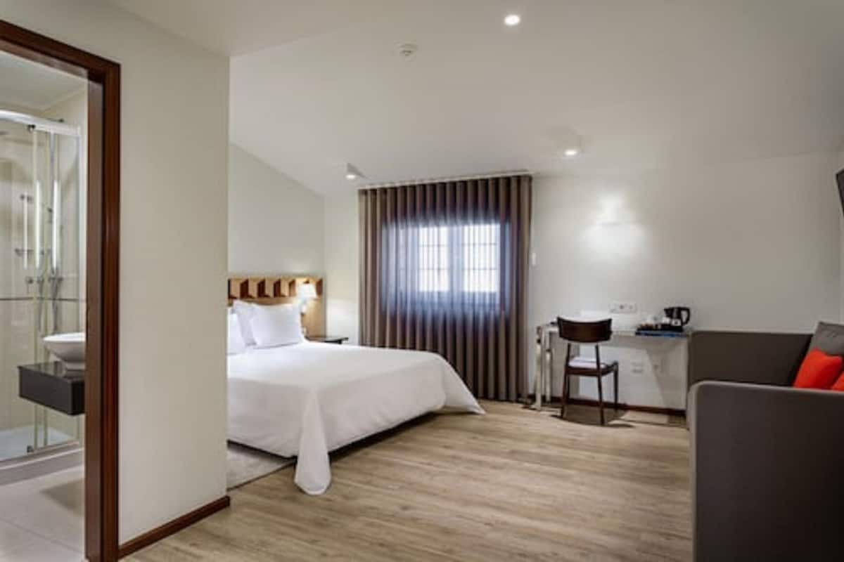 Ein Hotelzimmer mit einem Bett, einem Schreibtisch, einem Sessel und einer Couch.