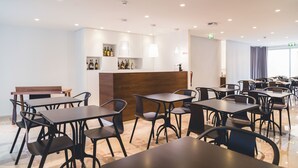 Un restaurante moderno con una barra central, varias mesas y sillas.