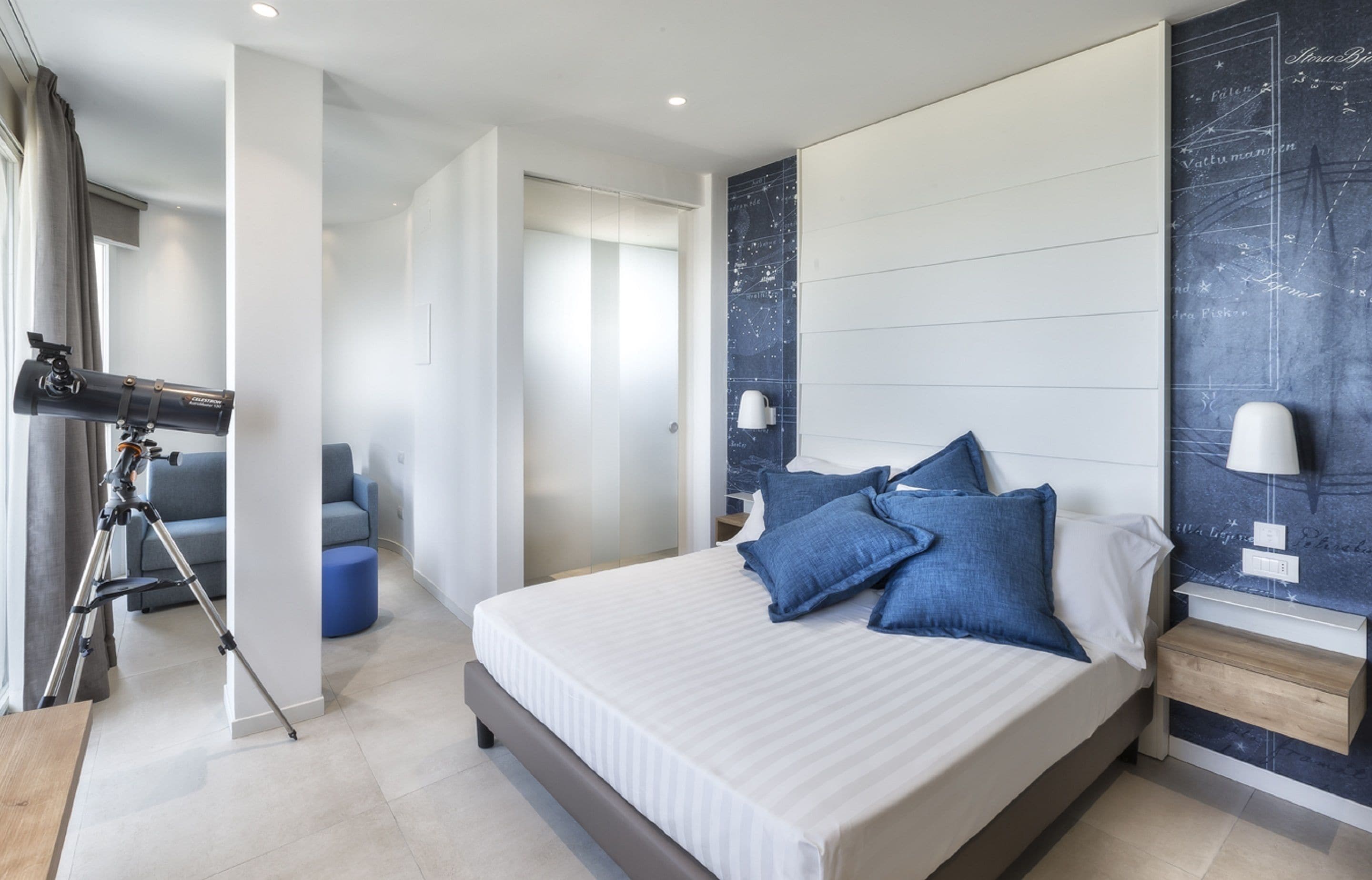 A modern bedroom with a large bed, a telescope, and a wall with a star map.