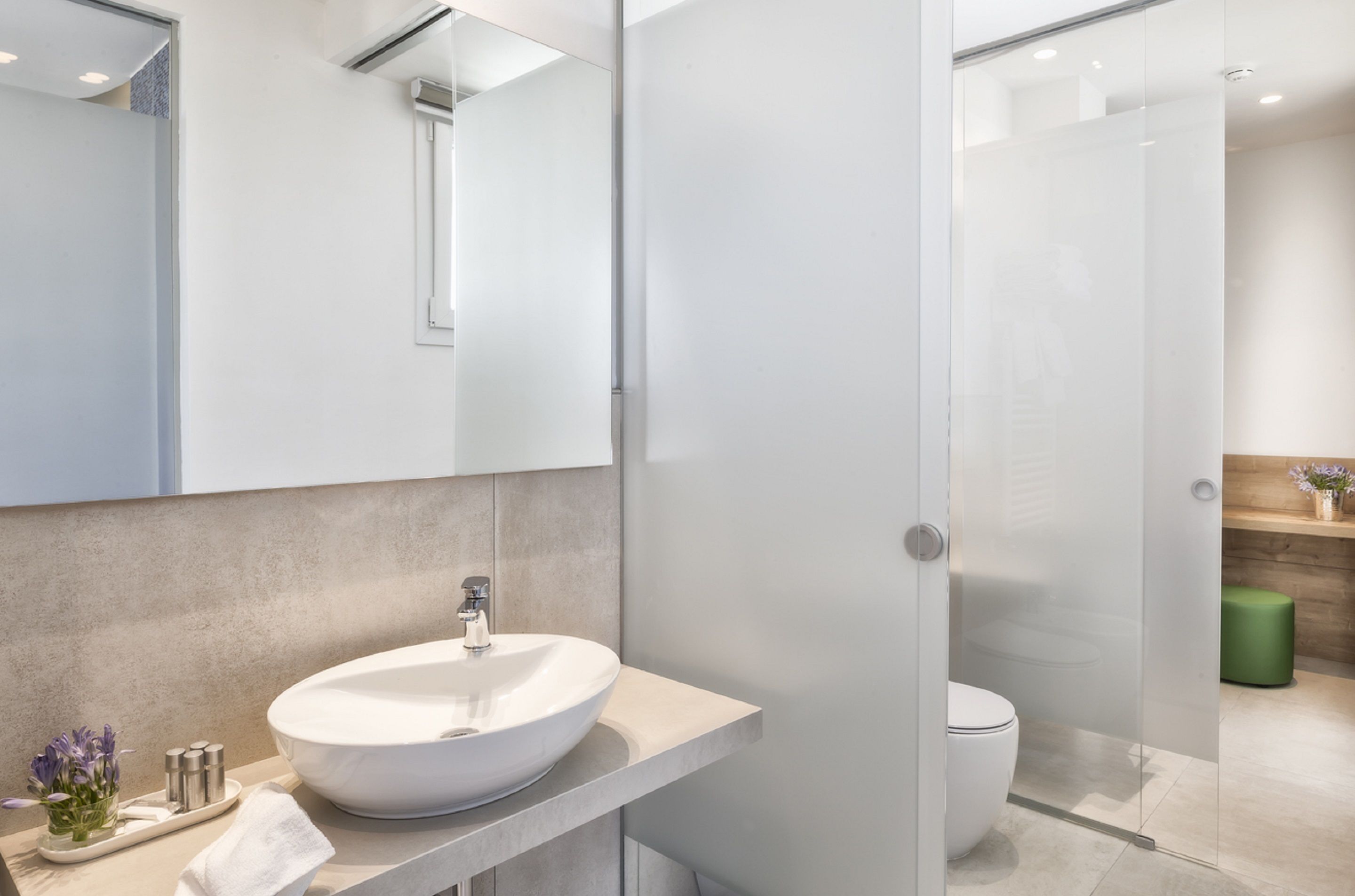 Une salle de bain moderne avec un grand lavabo blanc, un miroir et une cabine de douche en verre.