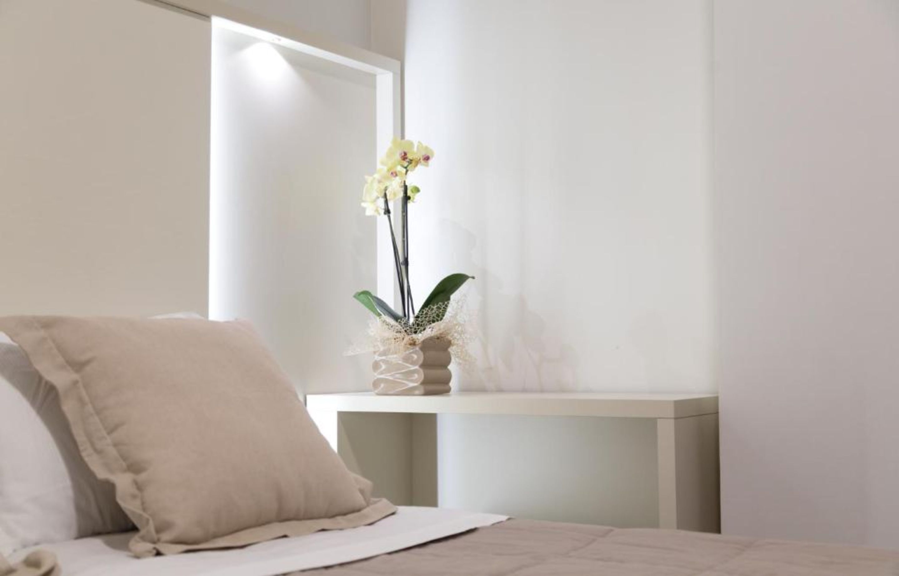 A bedroom with a bed, a bedside table, and a window with curtains.
