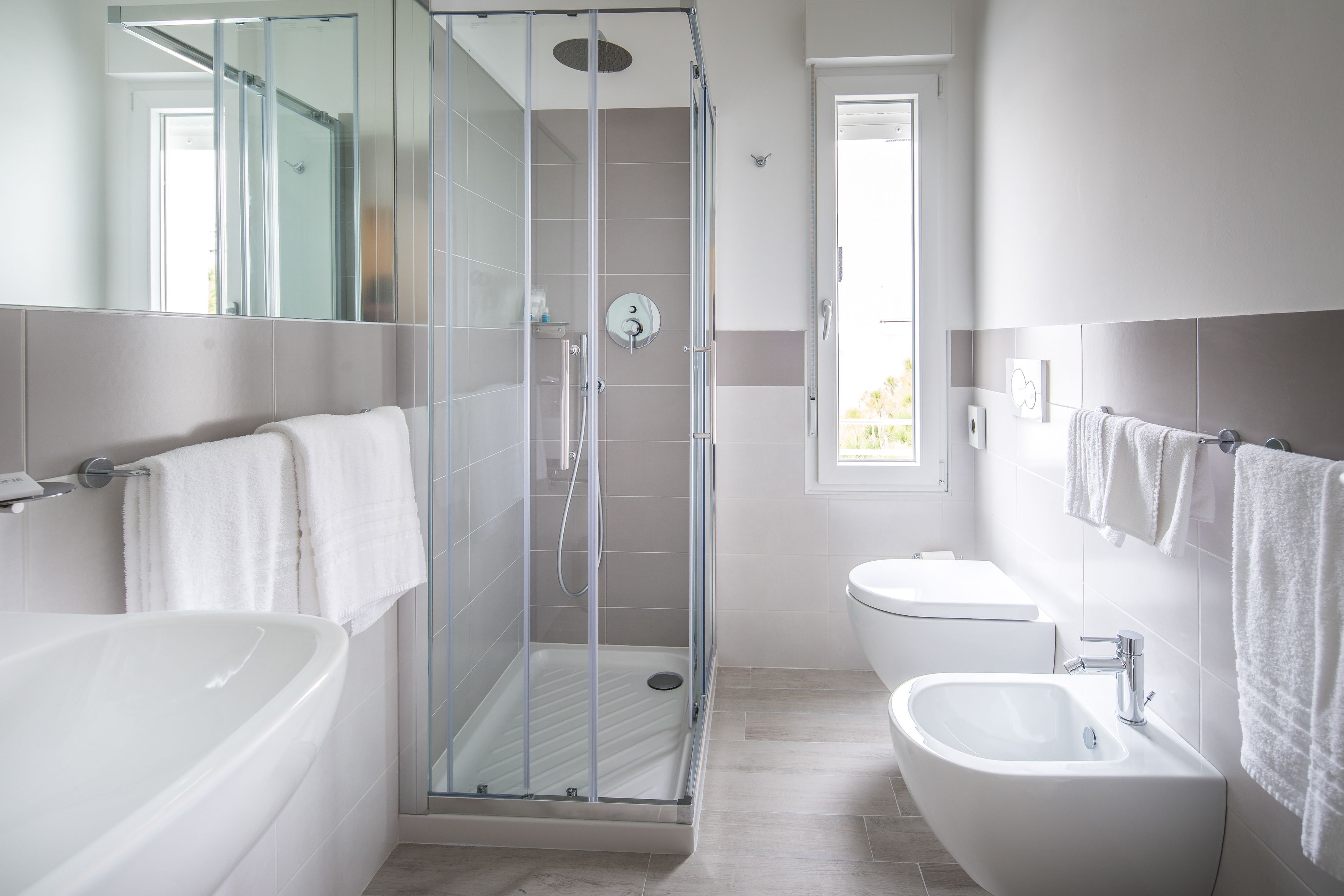 A modern bathroom with a glass-enclosed shower, a freestanding bathtub, and a pedestal sink.