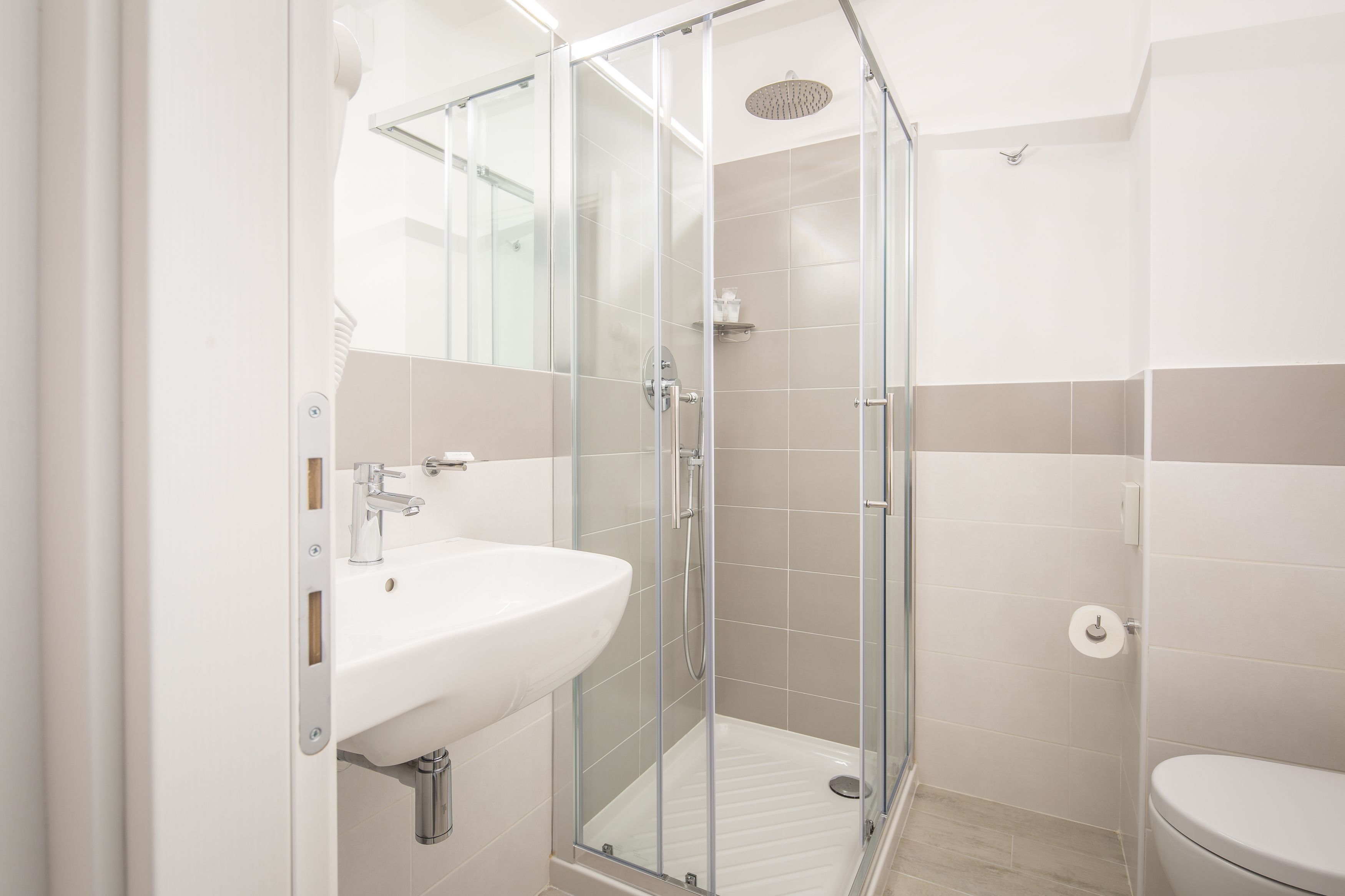 Un baño moderno con ducha envuelta en vidrio, un lavabo blanco y un inodoro.