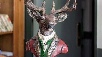 A deer head sculpture with antlers on a table, surrounded by books and a bowl.