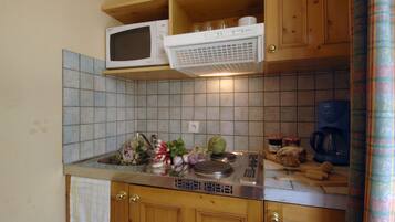 A kitchen with a microwave, sink, and various food items.