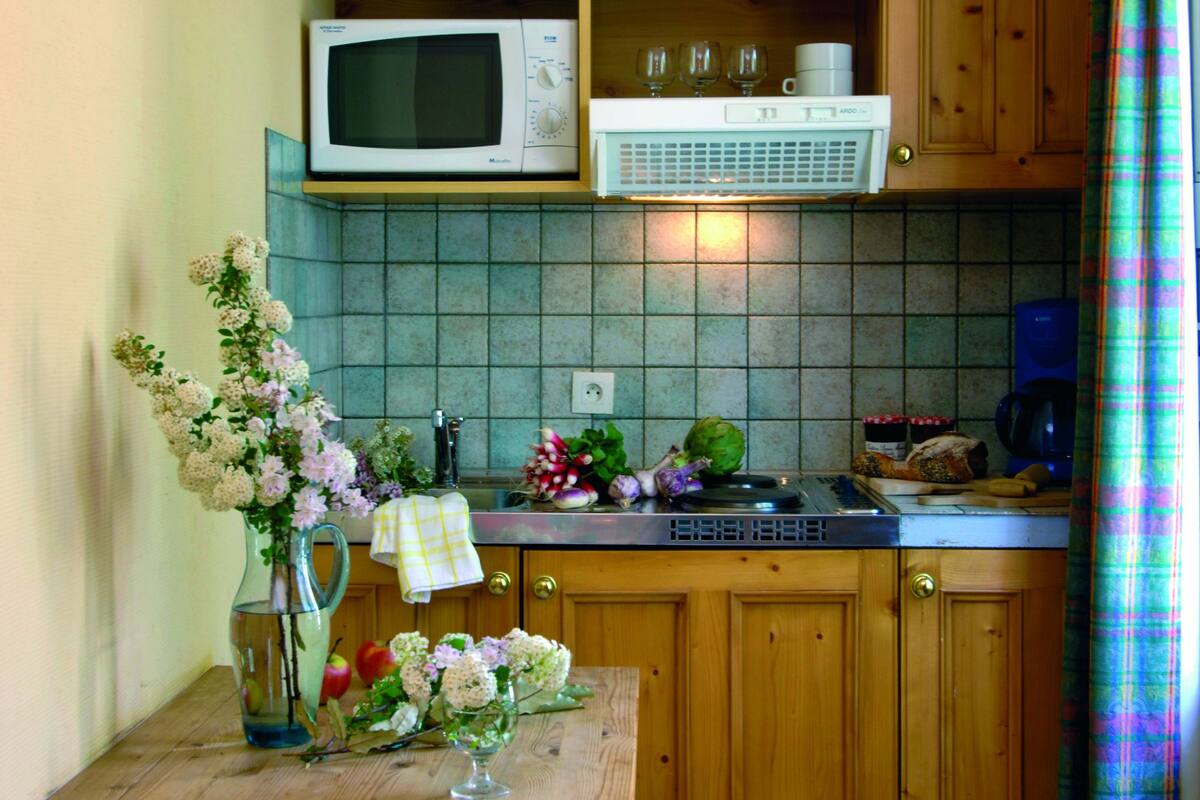 A small kitchen with wooden cabinets, a microwave, and a tiled backsplash.