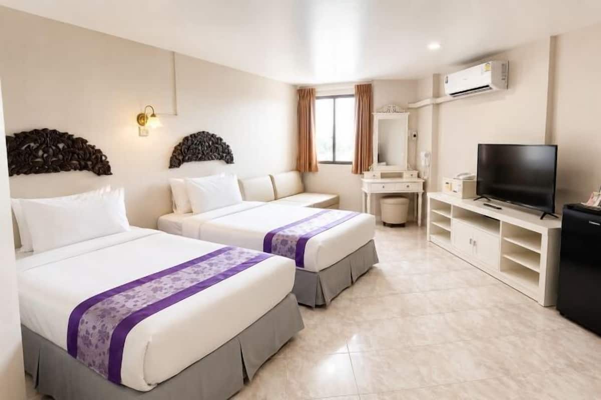 Habitación de hotel con dos camas, televisión, escritorio y espejo.