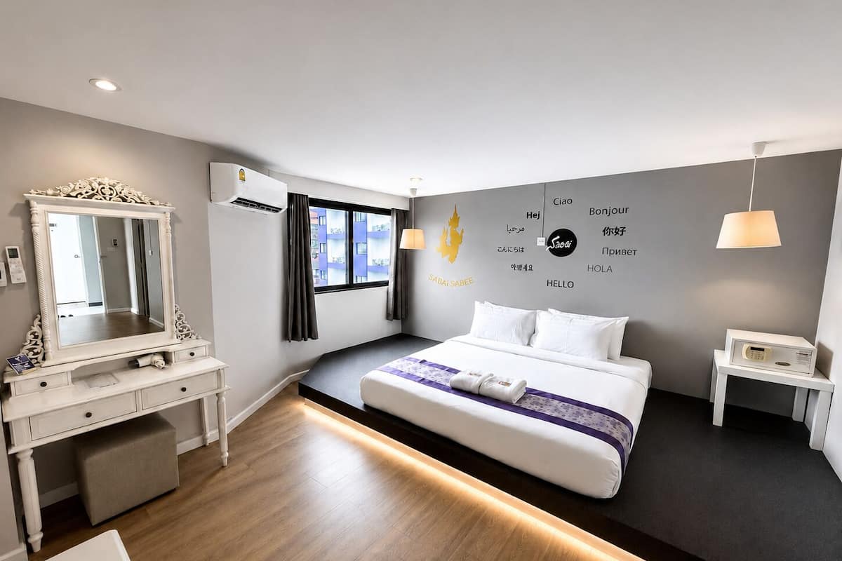 Una habitación de hotel moderna con cama, mesita de noche, cómoda y un espejo grande.