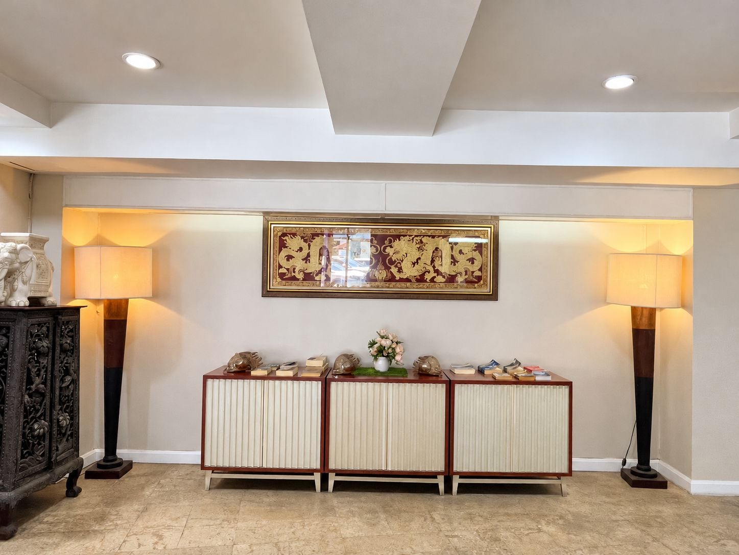 A reception area with a traditional Asian-style cabinet, two wall-mounted lamps, and a framed artwork above the cabinet.