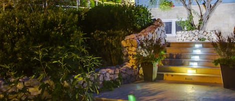 A building with a stone staircase leading to a door, surrounded by greenery.