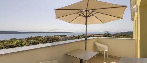 A balcony with a table, chairs, and a large umbrella.