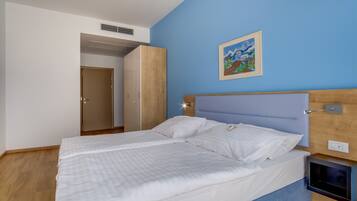 Una camera da letto con un letto, un armadio, un quadro appeso al muro e un comodino.