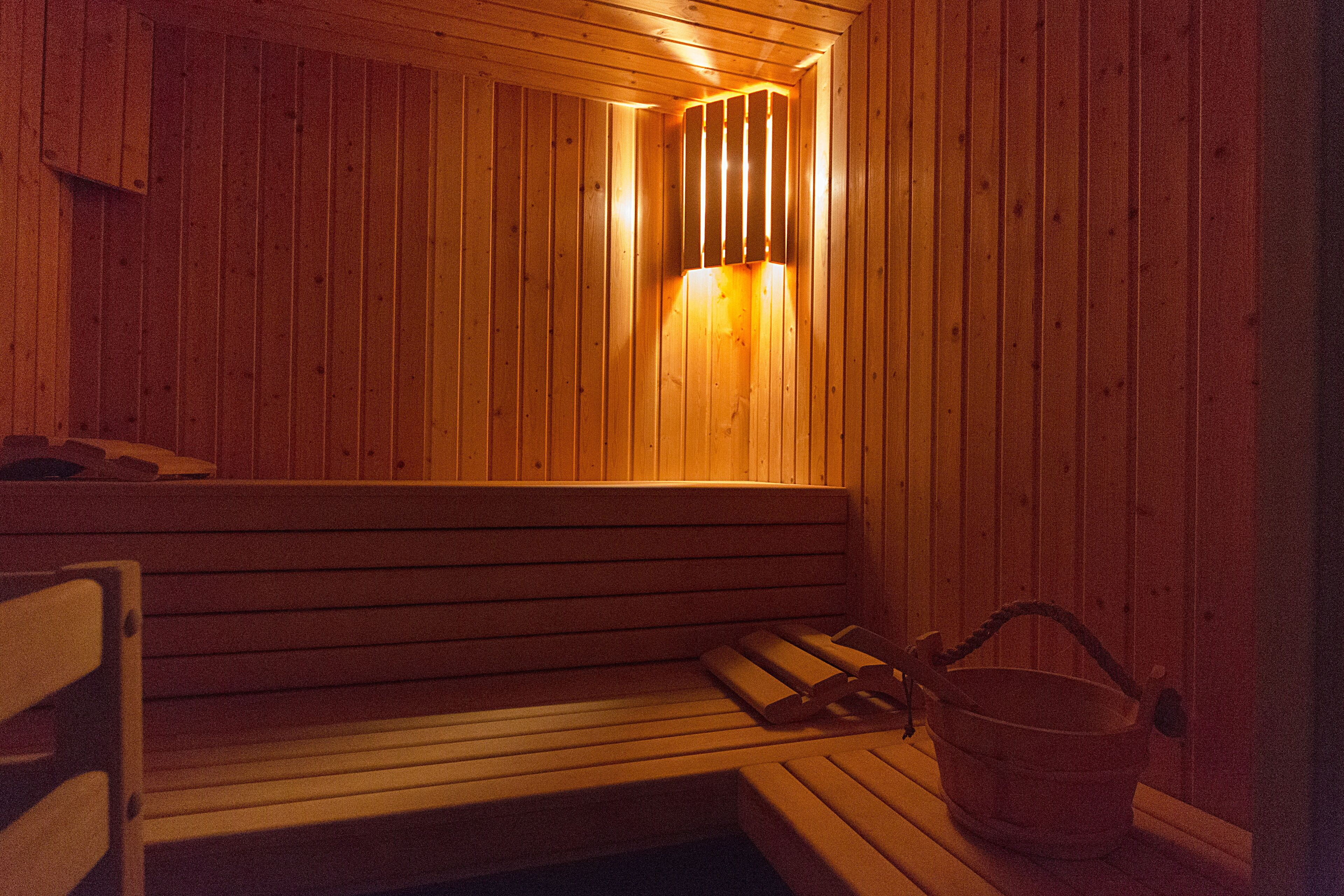 Una sauna in legno con panche e un catino.