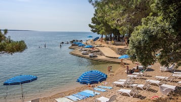Perto da praia, espreguiçadeiras, guarda-sóis, toalhas de praia