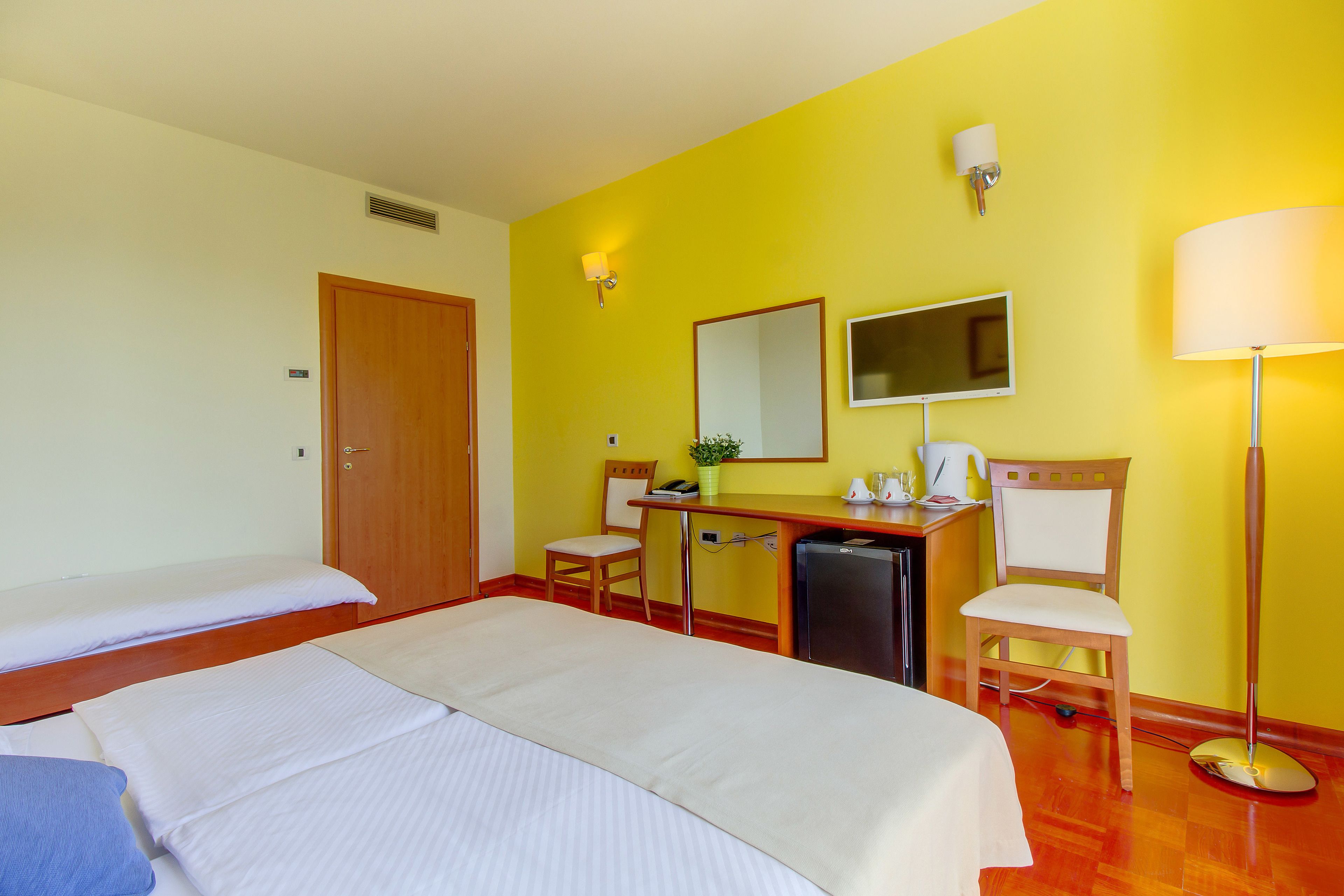 Een hotelkamer met een bed, een bureau, een stoel, een spiegel en een lamp.
