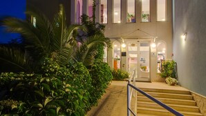 Un edificio con una escalera que lleva a una puerta, rodeado de vegetación.