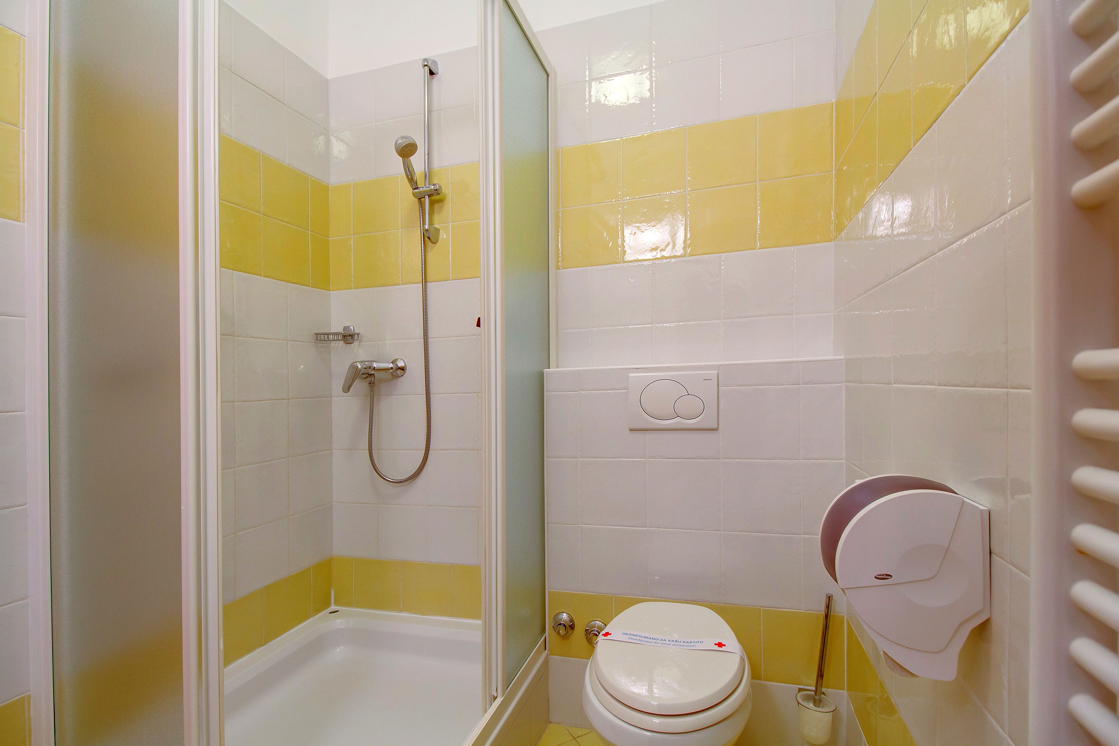 A bathroom with a shower, toilet, and a hand dryer.