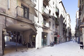 Una calle urbana estrecha con edificios de varios pisos, balcones y motocicletas estacionadas.
