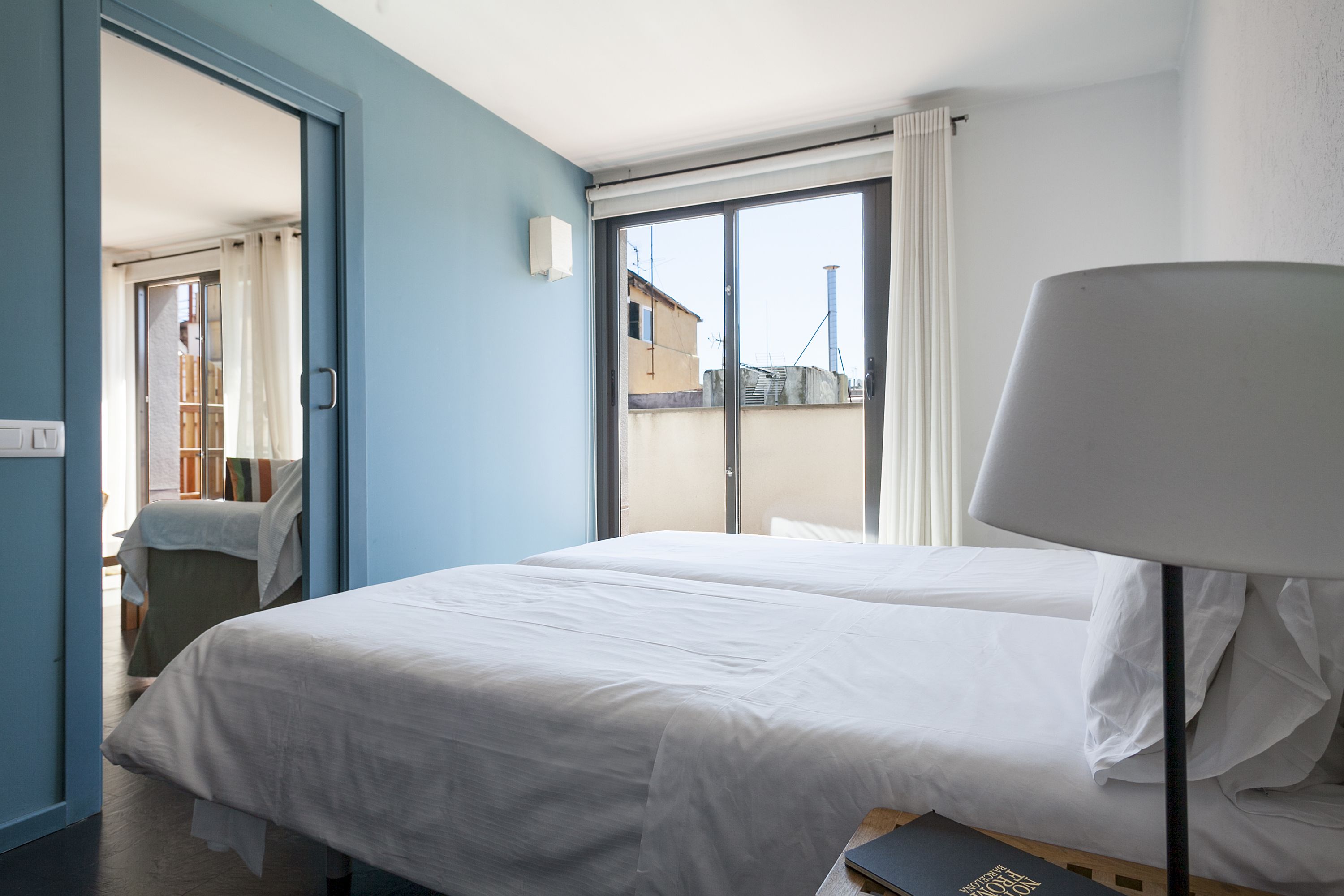A hotel room with two beds, a large window, and a lamp.