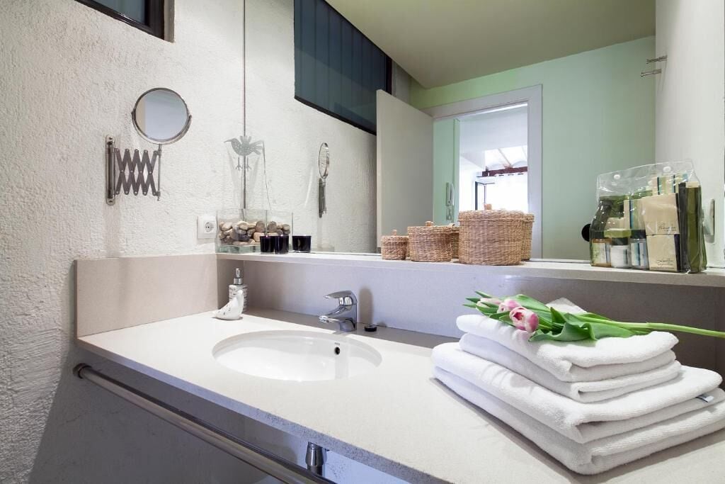 Une salle de bain équipée d’un lavabo, d’un miroir, d’une pile de serviettes et de produits de toilette.