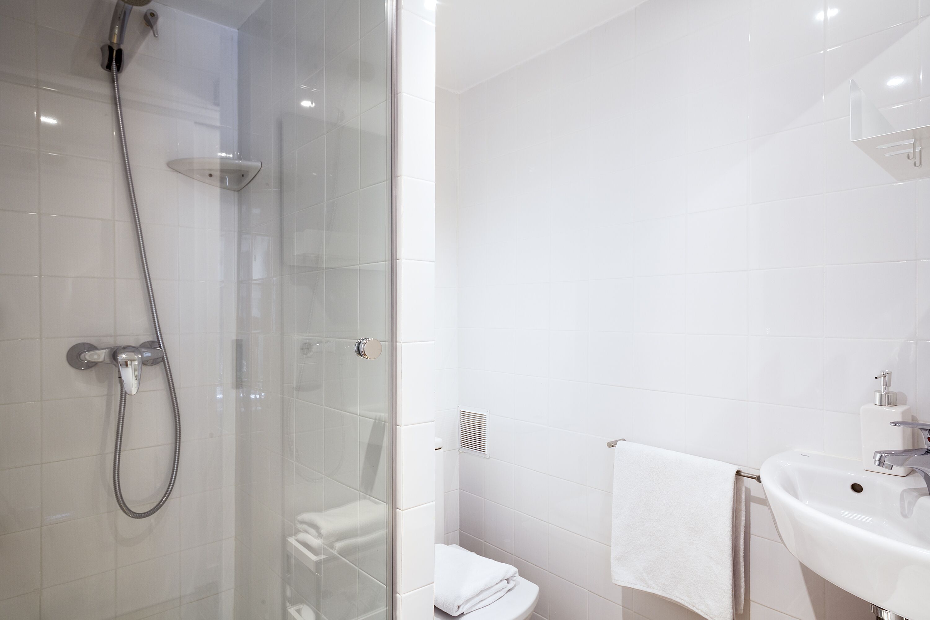 Ein modernes Badezimmer mit einer Duschkabine, einem weißen Waschbecken und einer Toilette.
