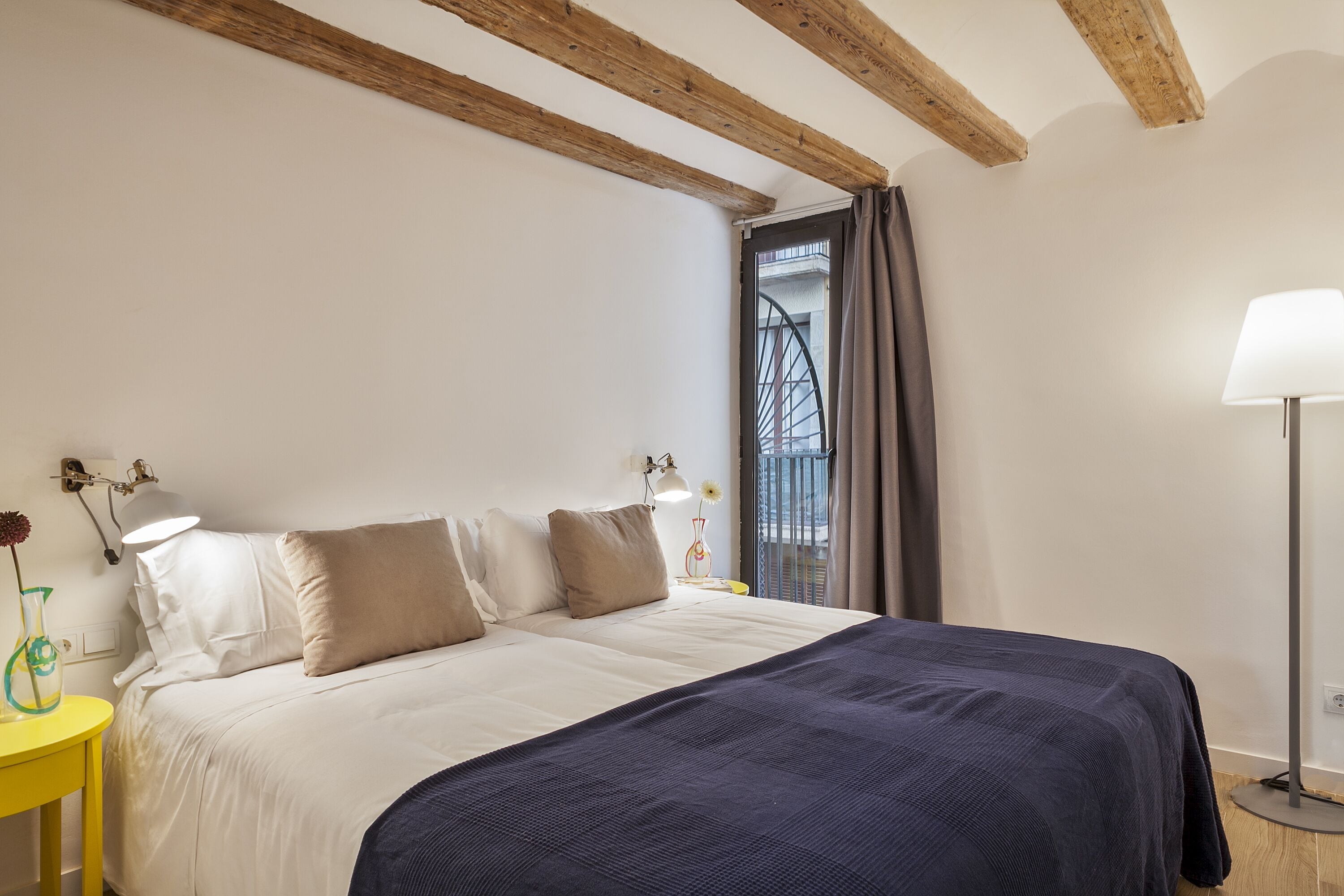 A bedroom with a bed, bedside lamps, a nightstand, and a floor lamp.