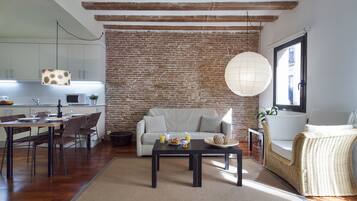 A modern living room with a brick wall, a white sofa, a dining table with chairs, and a coffee table.