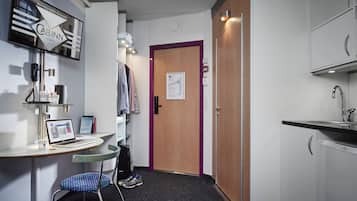 A hotel room with a desk, laptop, chair, and a door with a map.