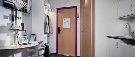 A hotel room with a desk, laptop, chair, and a door with a map.