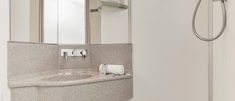 A modern bathroom with a sink, mirror, toilet, and shower.