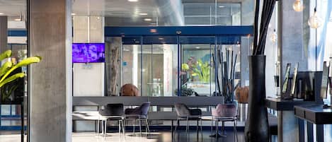 A modern lobby with seating, a reception desk, and a large window with a view.