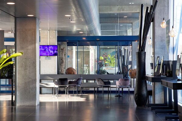 A modern lobby with seating, a reception desk, and a large window with a view. - CABINN Metro Hotel (Copenhagen)