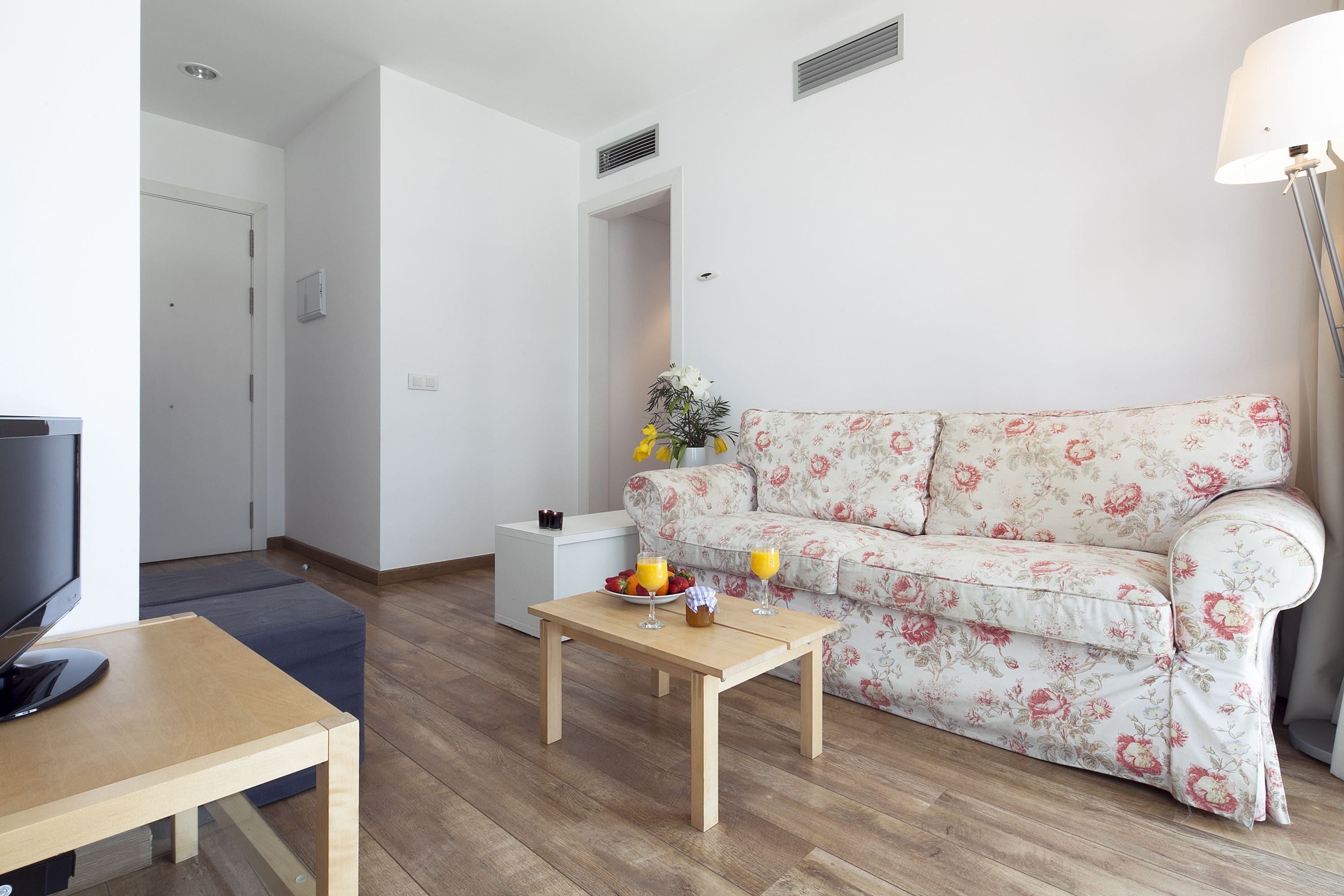 A living room with a sofa, a coffee table, a TV, and a lamp.