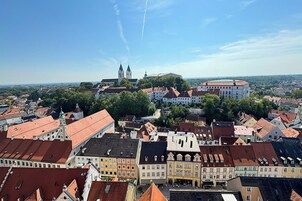 Un paisaje urbano con edificios históricos, una iglesia destacada con dos torres gemelas y un gran edificio circular.