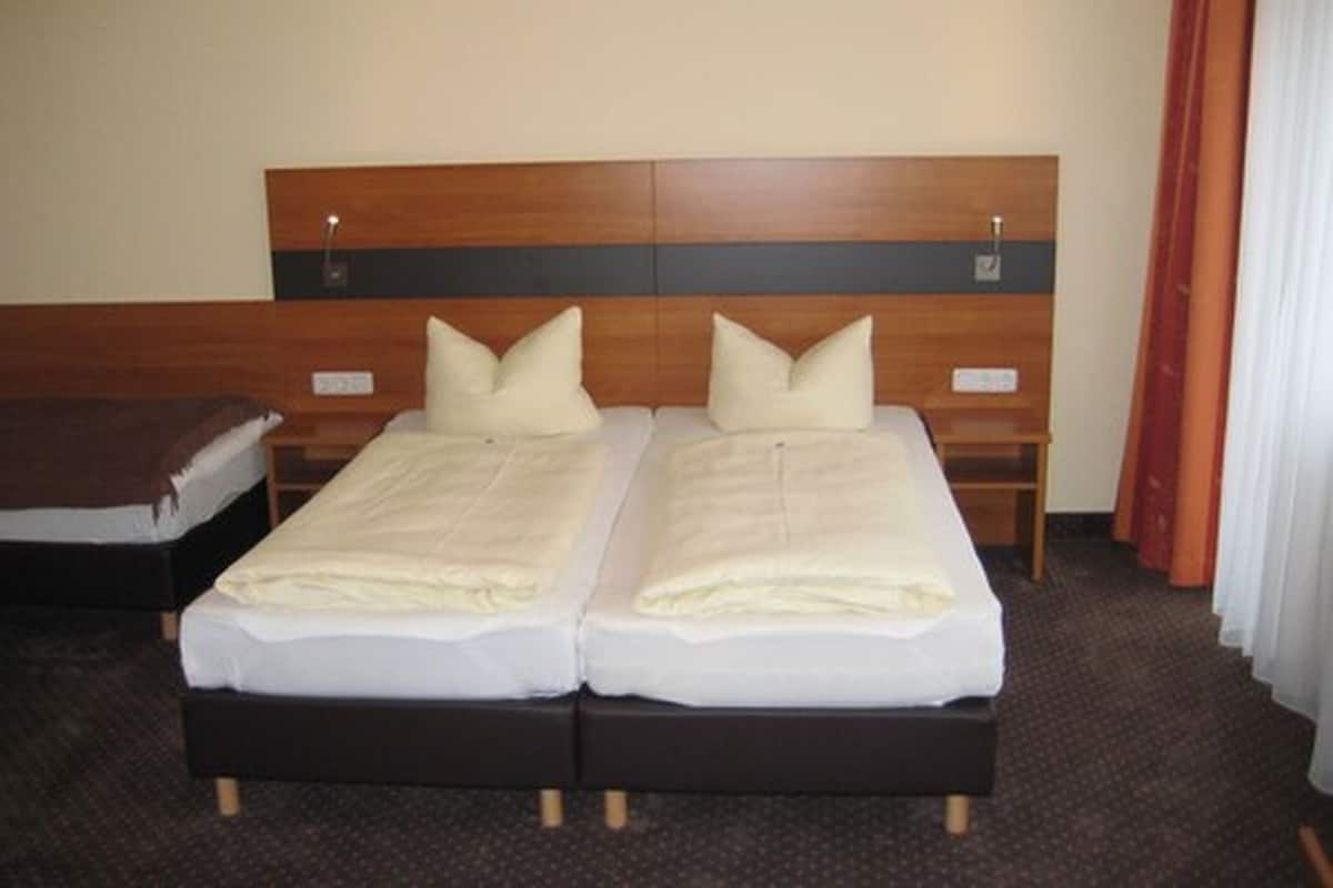 Una habitación de hotel con dos camas individuales, cabeceros de madera y suelo alfombrado.
