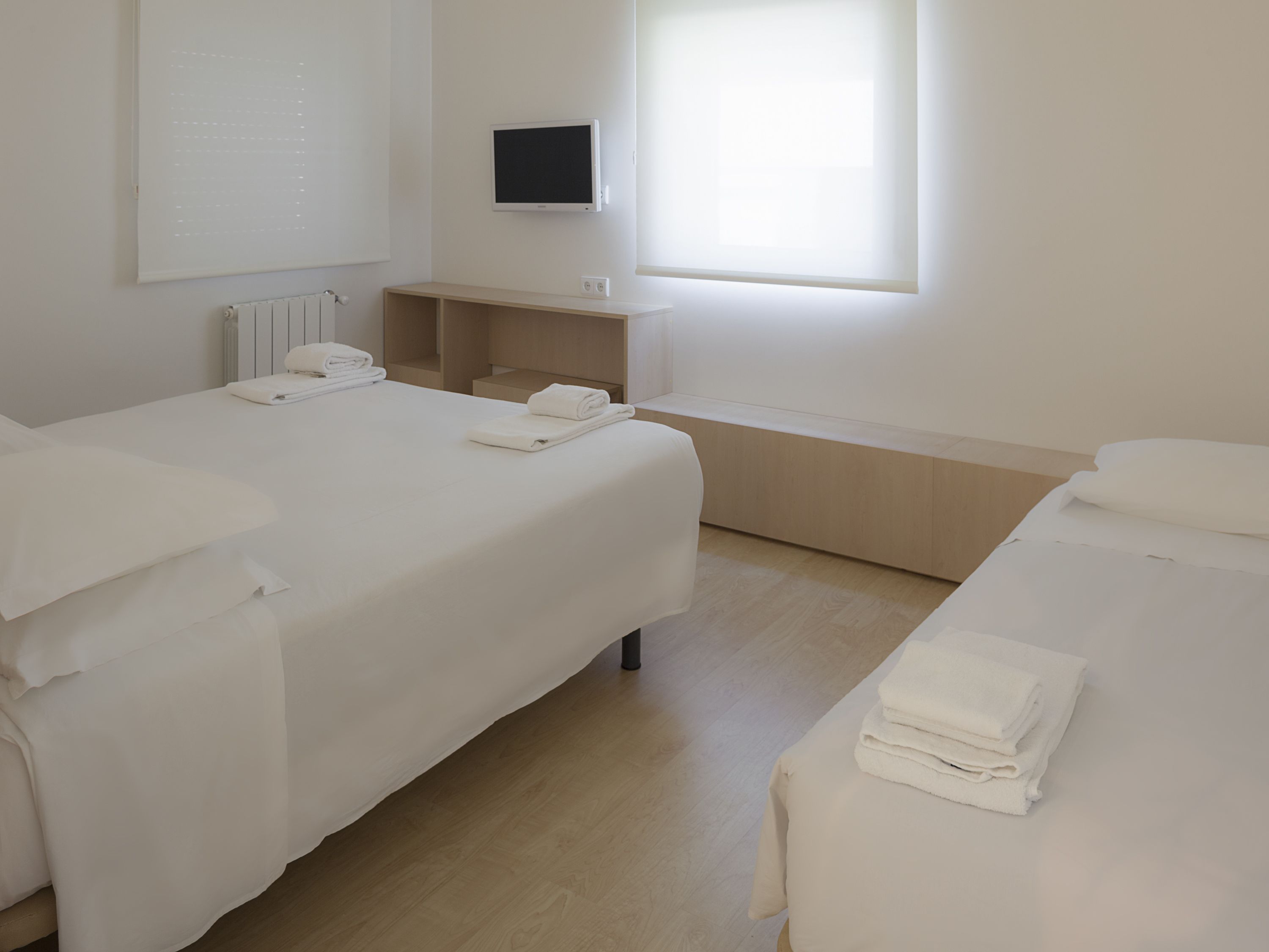 Habitación de hotel con dos camas, un televisor y una ventana.