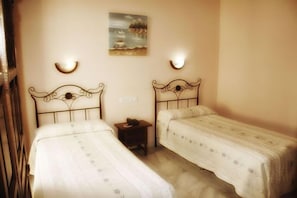 A bedroom with two single beds, a nightstand, and a painting on the wall. - El Triunfo (Córdoba)