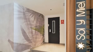 A staircase with a wall mural, a black door, and a sign with illuminated text. - Sol y Miel Hostal (Benalmádena)