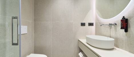A modern bathroom with a toilet, a sink, a mirror, and a shower area.