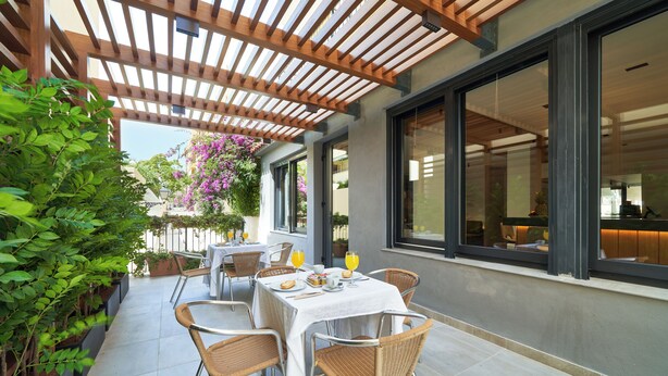 An outdoor patio with a wooden pergola, tables with chairs, and potted plants. - Sol y Miel Hostal (Benalmádena)