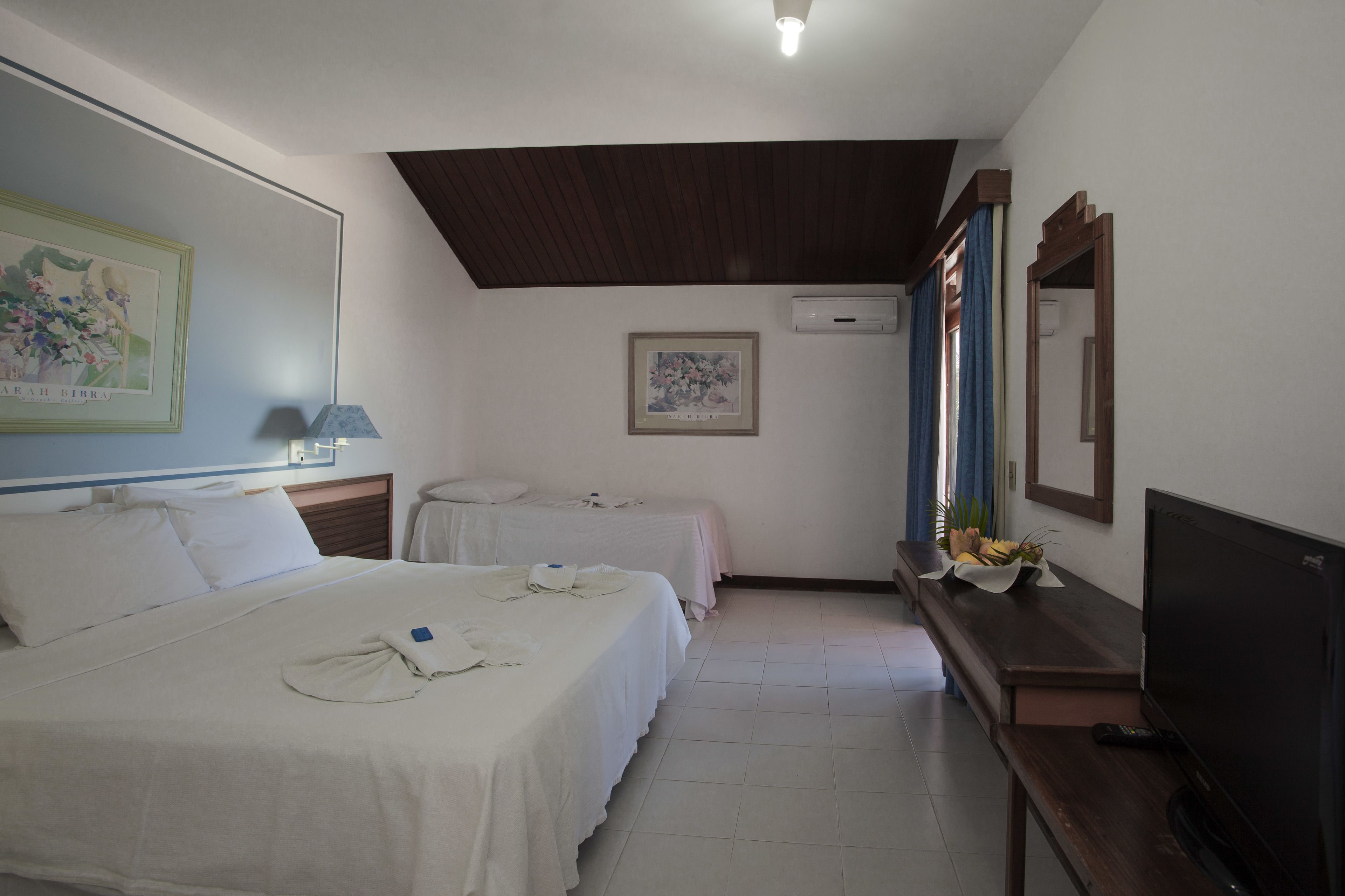 Habitación de hotel con dos camas, televisión, escritorio y espejo.
