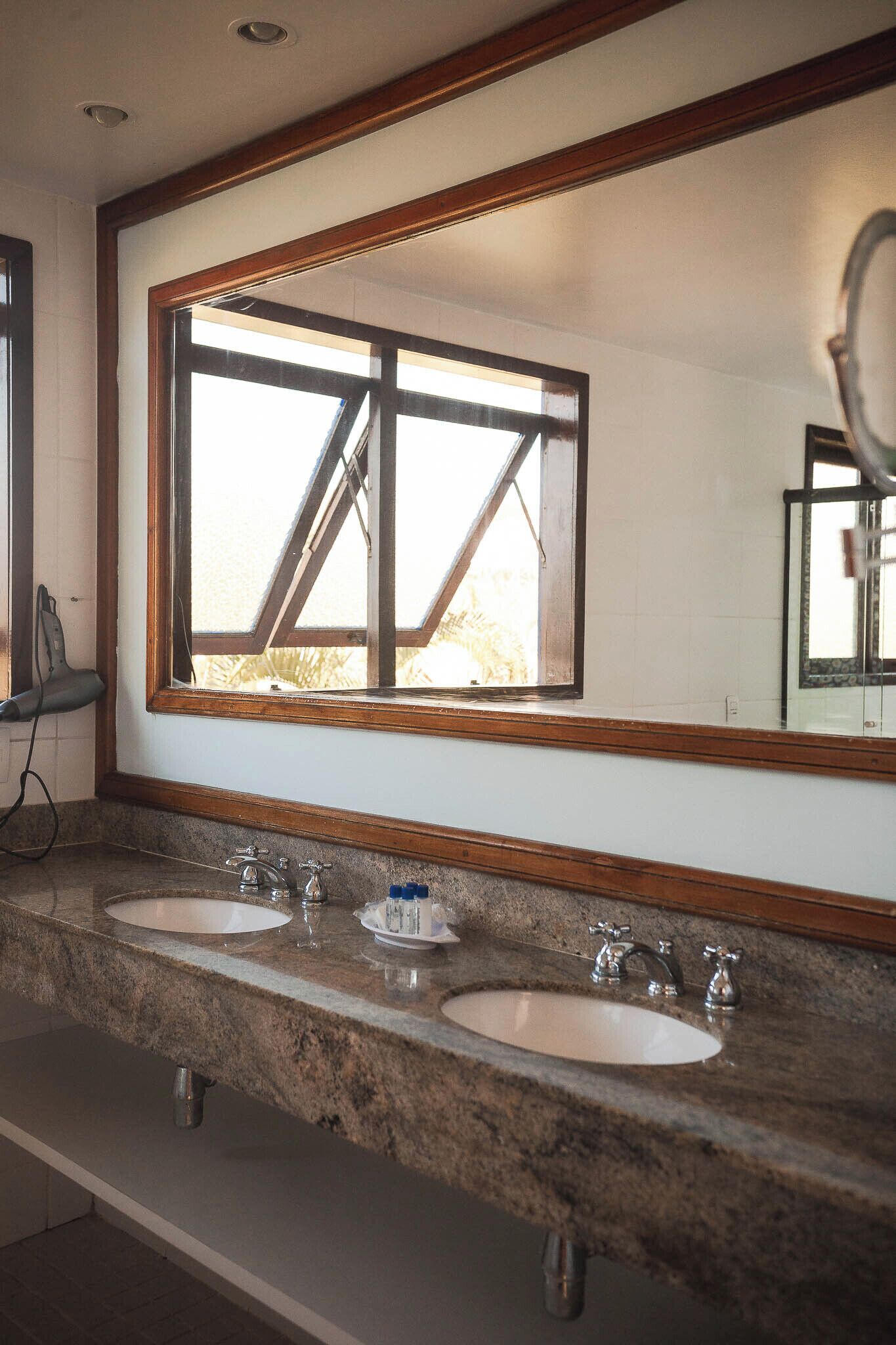 A bathroom with two sinks, a large mirror, and a window.