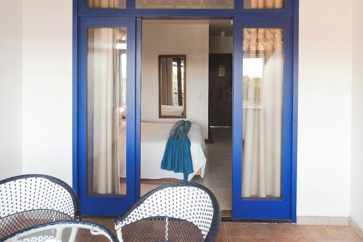 A room with a bed, a chair, and a blue-framed door.