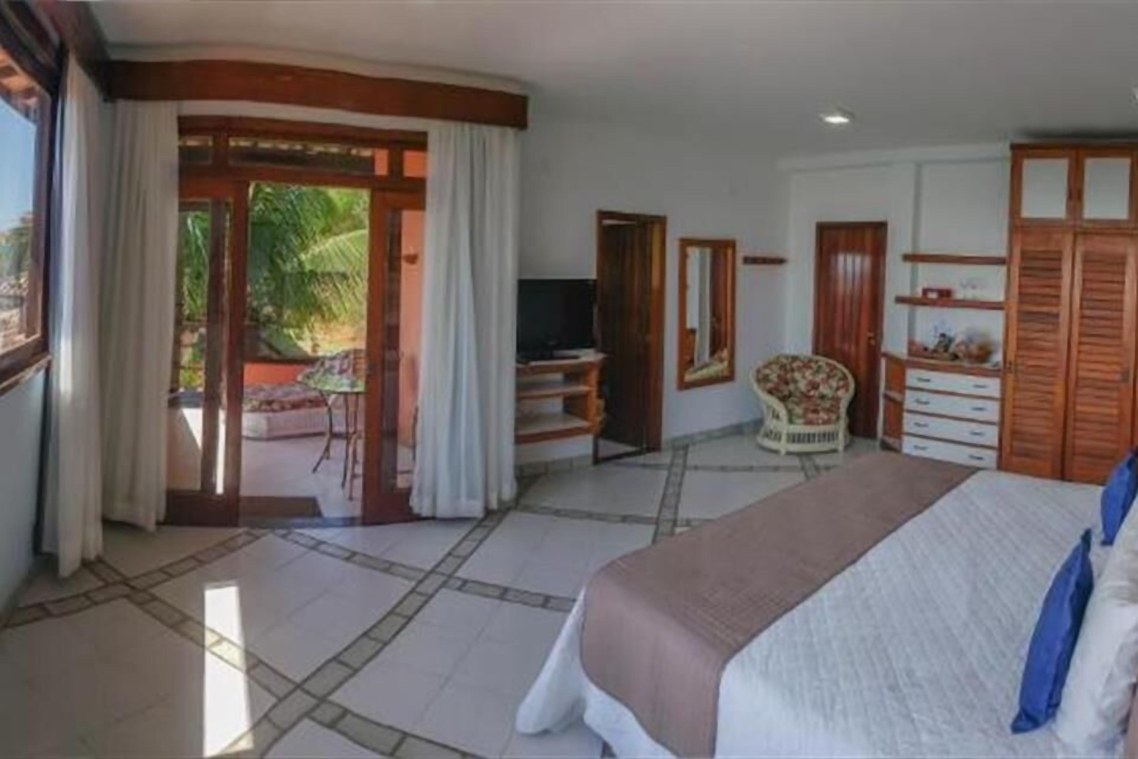 A bedroom with a bed, a television, a chair, and a wardrobe.