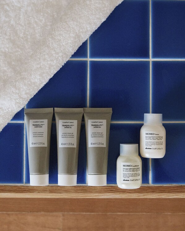 Une étagère contenant des produits de soins pour la peau, notamment un après-shampoing, un gel douche et une lotion.
