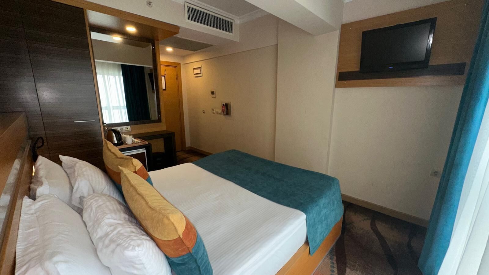 Ein Hotelzimmer mit Bett, Schreibtisch, Spiegel, Fernseher und Bad.